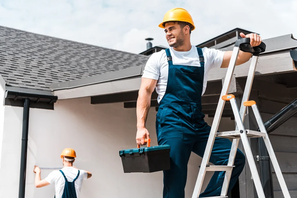 Two professionals performing roof gutter maintenance on a residential property